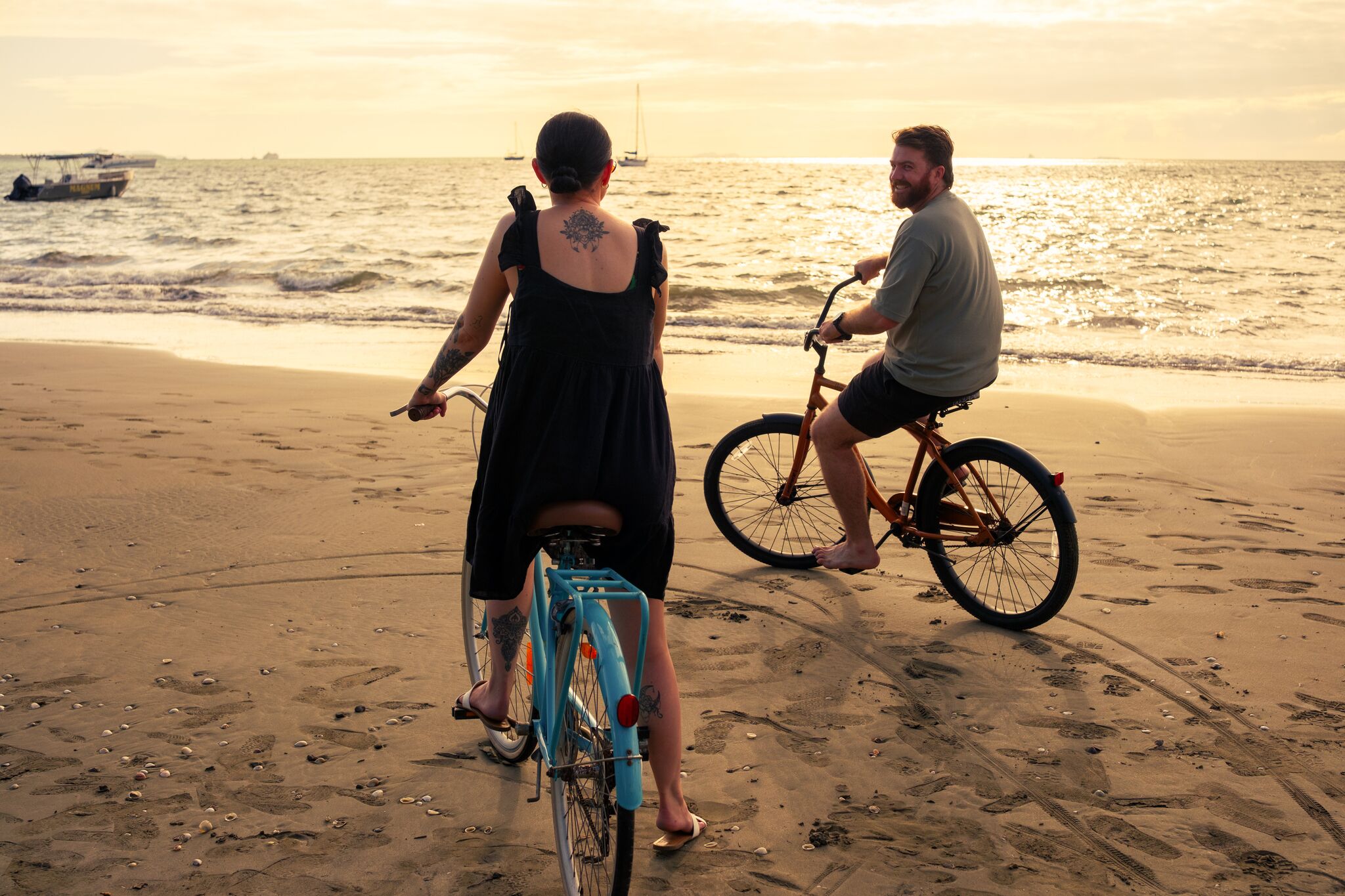 Una playa con orilla arenosa, una bicicleta azul y una persona montando en bicicleta.