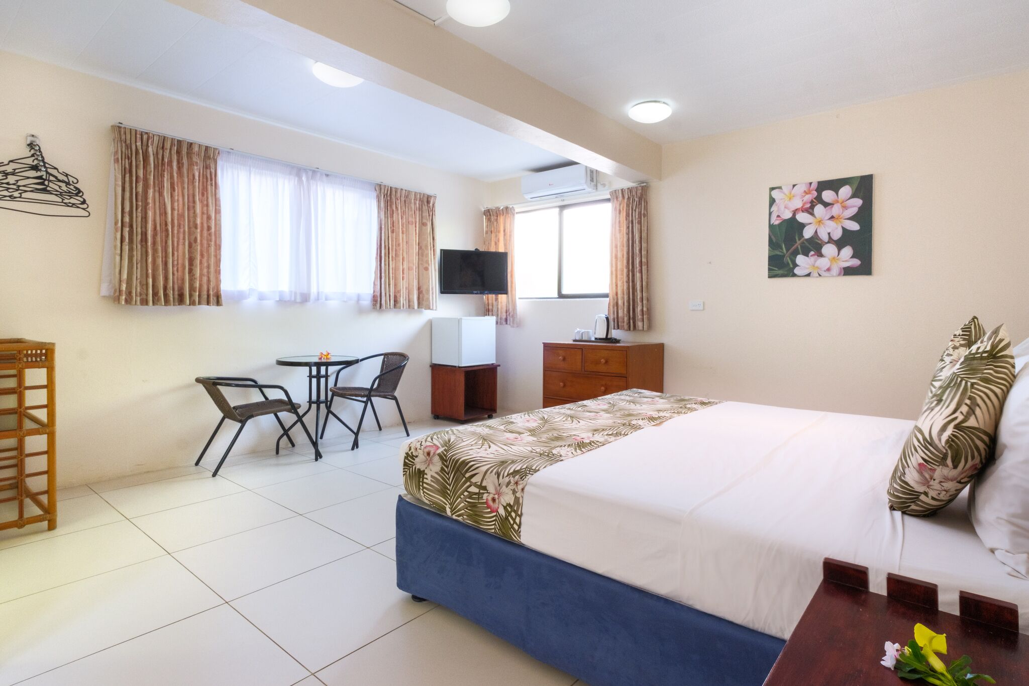 Una camera d'albergo con un letto, una scrivania, una sedia, una televisione e una finestra con tende.