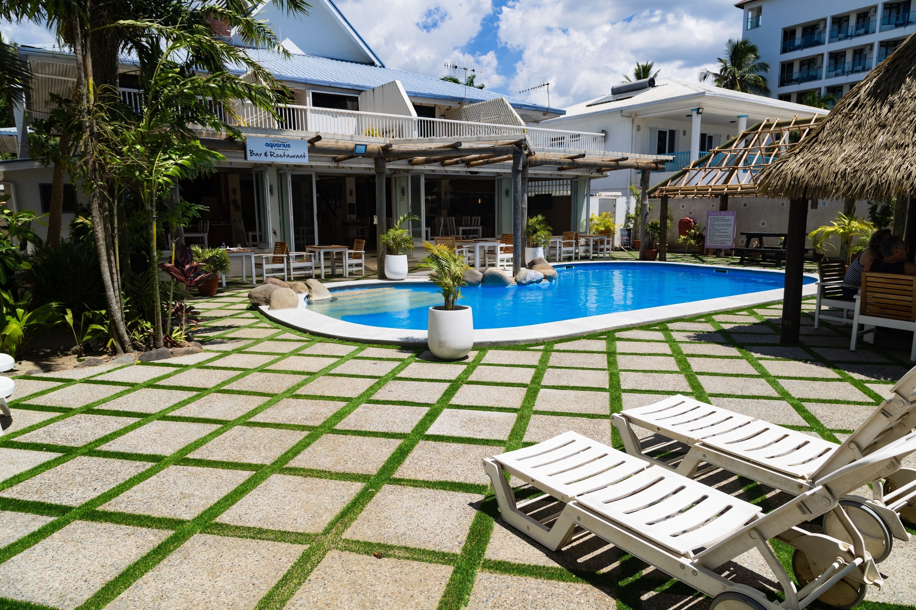 A pool area with lounge chairs, a bar, and a restaurant.