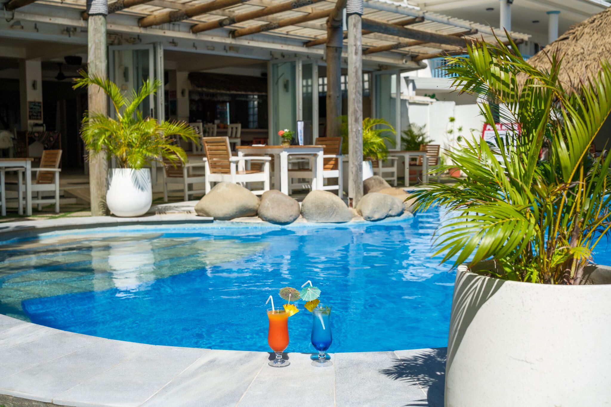 Un espace piscine comprenant deux chaises, une table et des plantes en pot.