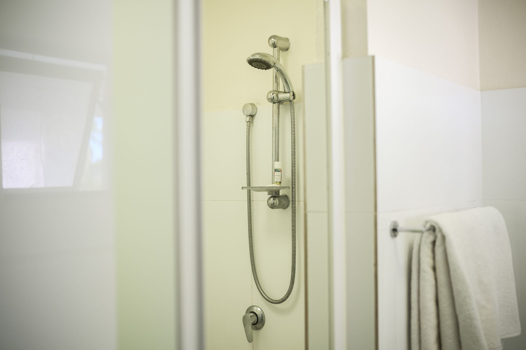 A shower with a handheld showerhead and a handheld hose.