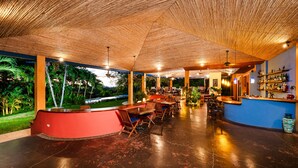 An indoor dining area with a curved red counter, wooden tables, and chairs. - Hotel Luna Azul (Cuajiniquil)