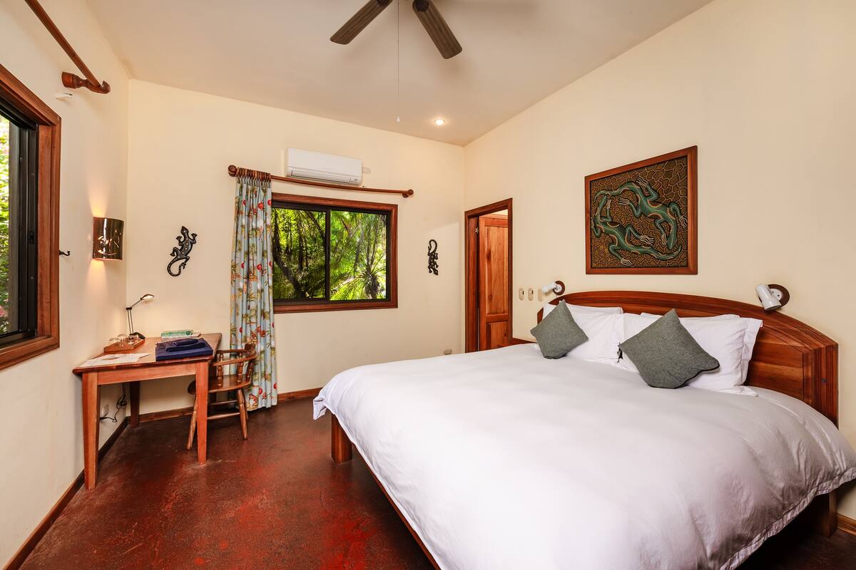 A bedroom with a large bed, a desk, and a window with curtains.