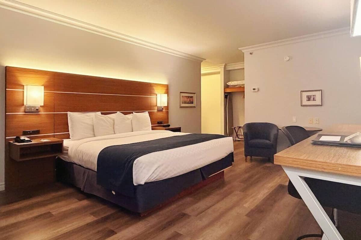A hotel room with a large bed, bedside tables, a desk, and a chair.