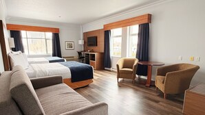 A hotel room with a bed, two armchairs, a sofa, a desk, and a TV.