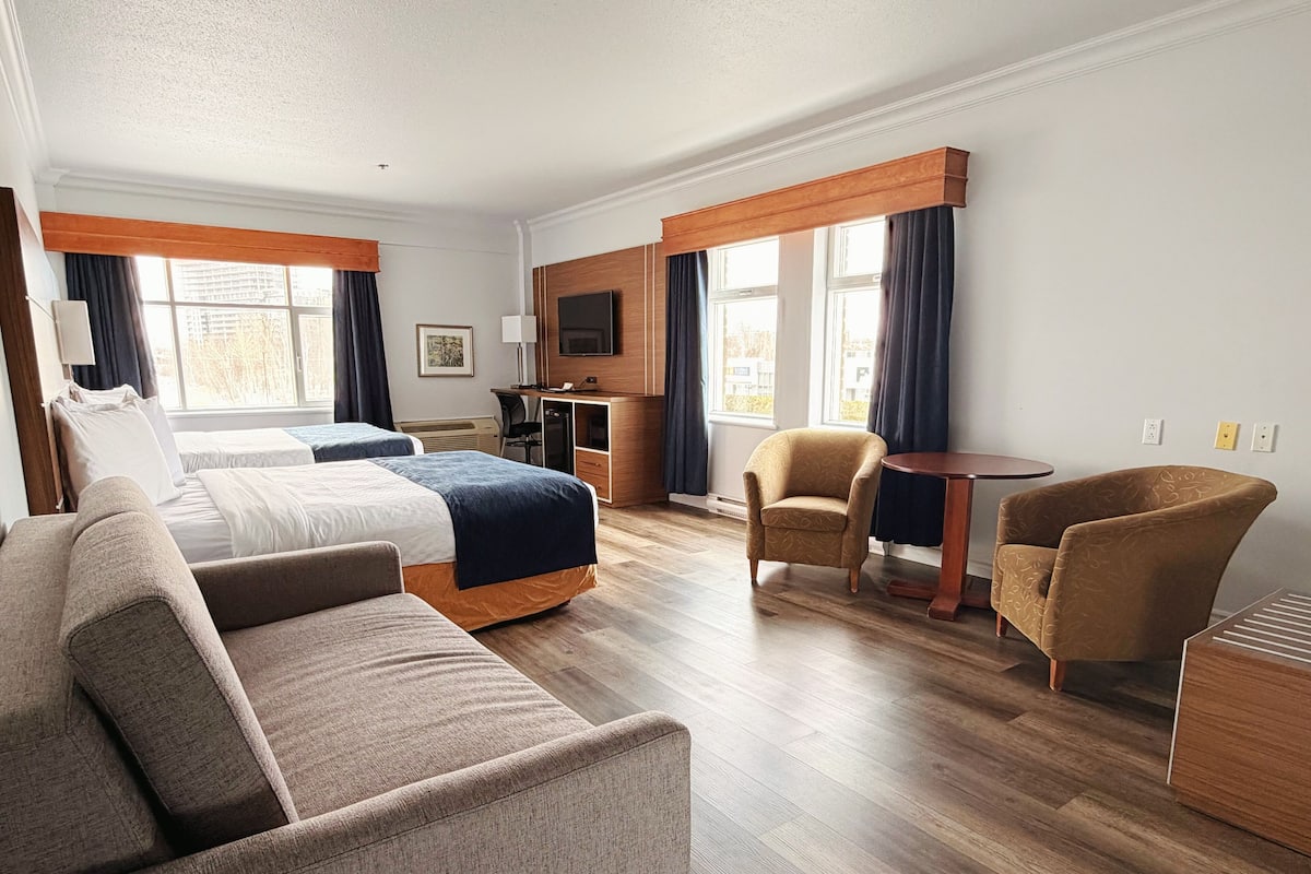 A hotel room with a bed, two armchairs, a sofa, a desk, and a TV.