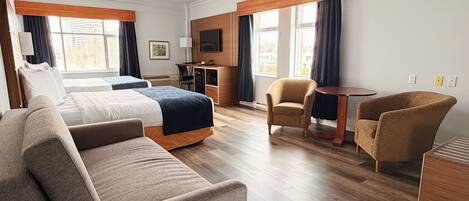 A hotel room with a bed, two armchairs, a sofa, a desk, and a TV.
