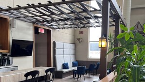 A restaurant with a brick counter, black chairs, a sofa, and a hanging light fixture. - Hotel L'Oie des neiges (Levis)
