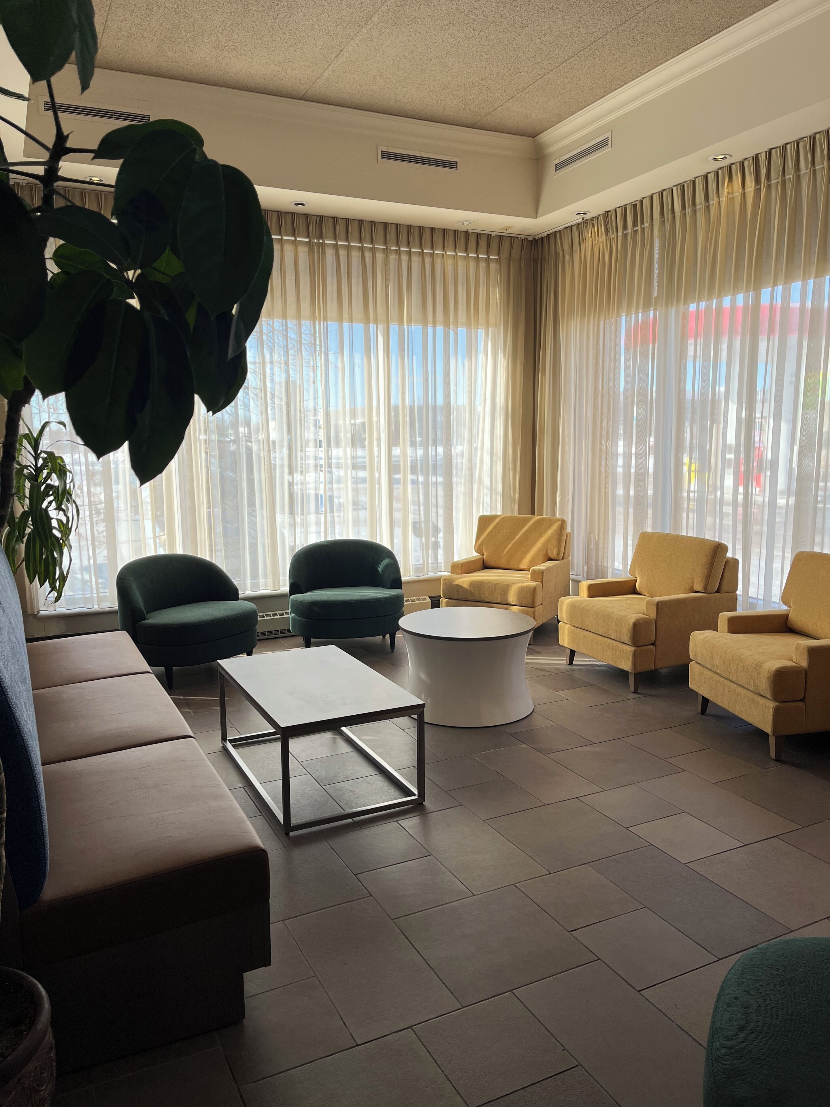 A modern living room with a sofa, armchairs, a coffee table, and a large window with curtains.