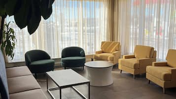 A modern living room with a sofa, armchairs, a coffee table, and a large window with curtains.