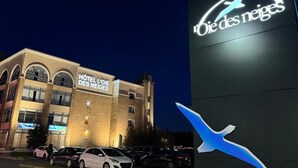 A hotel building with a sign reading 'HOTEL L'OE DES NEIGES' and a logo with a stylized bird. - Hotel L'Oie des neiges (Levis)