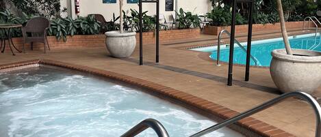 Una piscina con hidromasaje, rodeada de plantas en macetas y mobiliario de exterior.