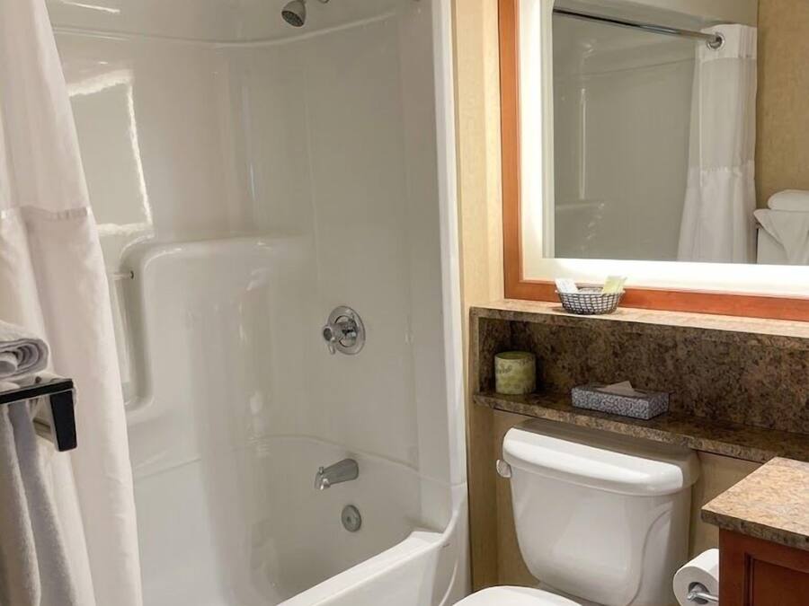 A bathroom with a bathtub, toilet, and a mirror above the sink.