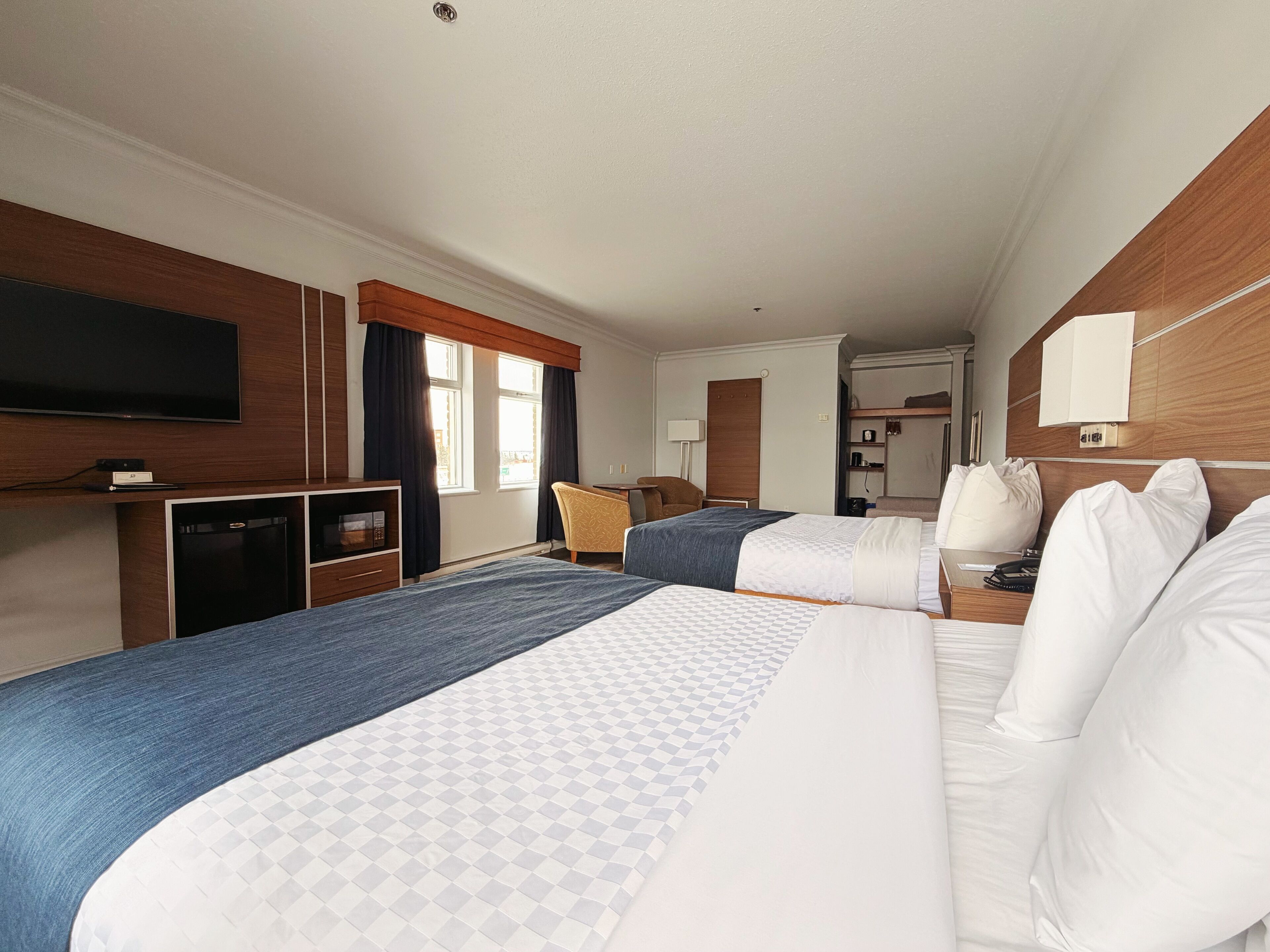 A hotel room with two beds, a TV, a desk, and a wardrobe.