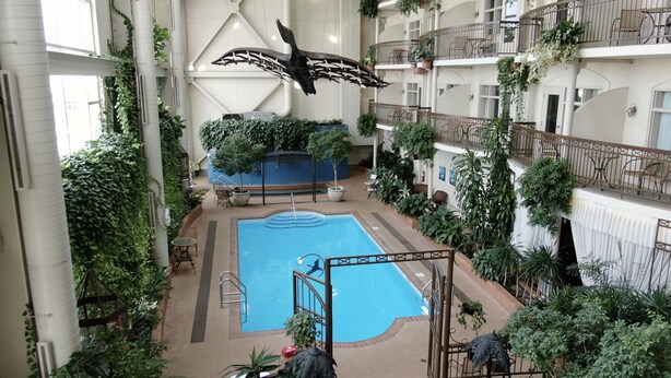An indoor swimming pool surrounded by greenery, with multiple balconies and seating areas.
