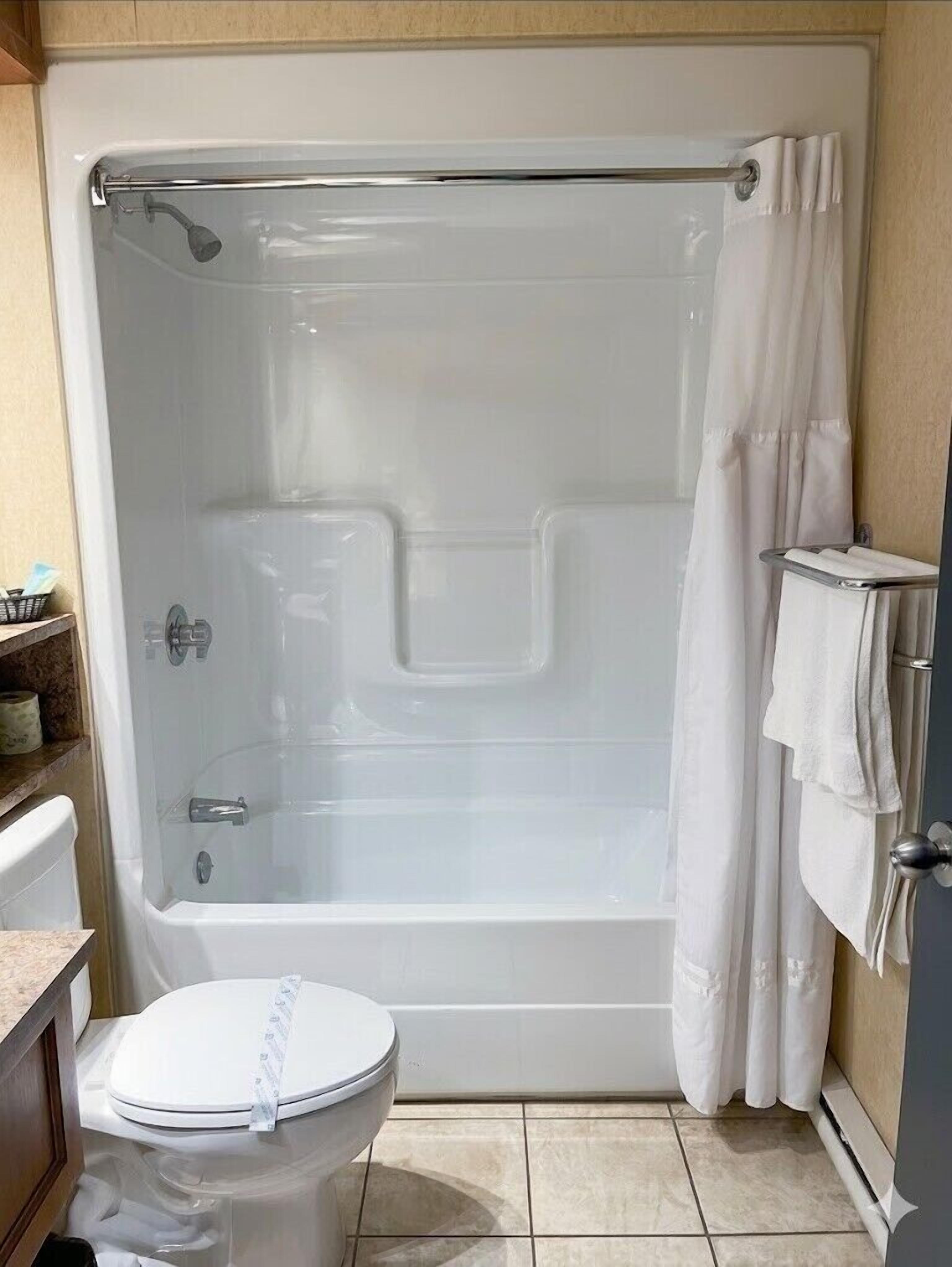 A bathroom with a bathtub, toilet, and a shower curtain.