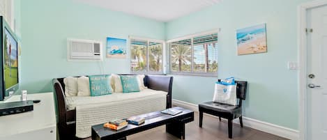 Una habitación con cama, escritorio, silla, mesa de centro y ventilador de techo.