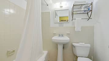 A bathroom with a bathtub, a sink, a toilet, and a shelf with toiletries.