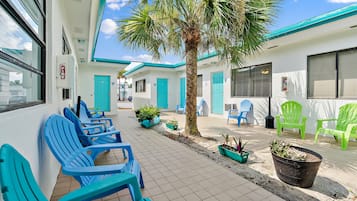 A clean, well-maintained outdoor seating area with blue chairs and potted plants, suggesting a welcoming environment for guests.