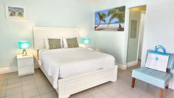 A bedroom with a bed, two bedside tables with lamps, a wall-mounted picture, and a door.