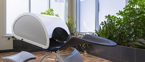 Un cuarto de tratamientos médicos con una silla reclinable, un recipiente para pies y plantas en macetas.