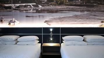A hotel room with two beds, a nightstand, and a wall-mounted light.