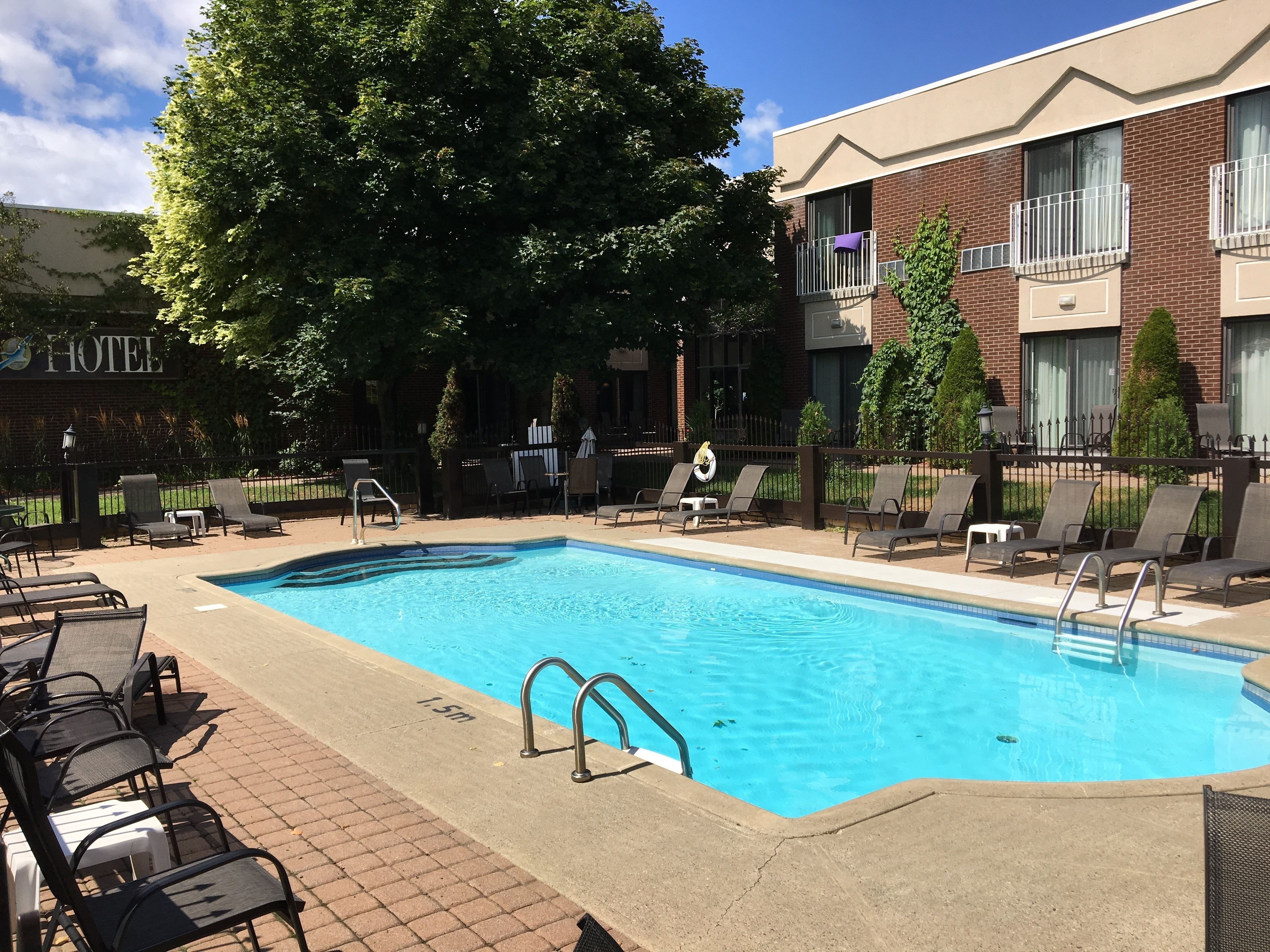 A swimming pool with lounge chairs and a brick building in the background.