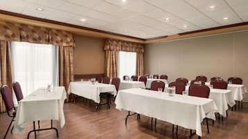 Un salón de conferencias con varias mesas y sillas, dispuestas en filas.