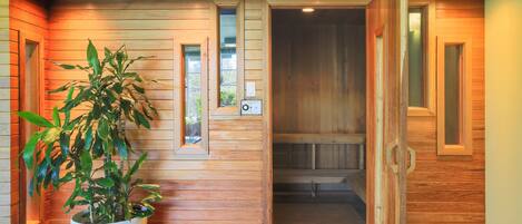A wooden interior hallway with a potted plant, wooden doors, and recessed lighting.