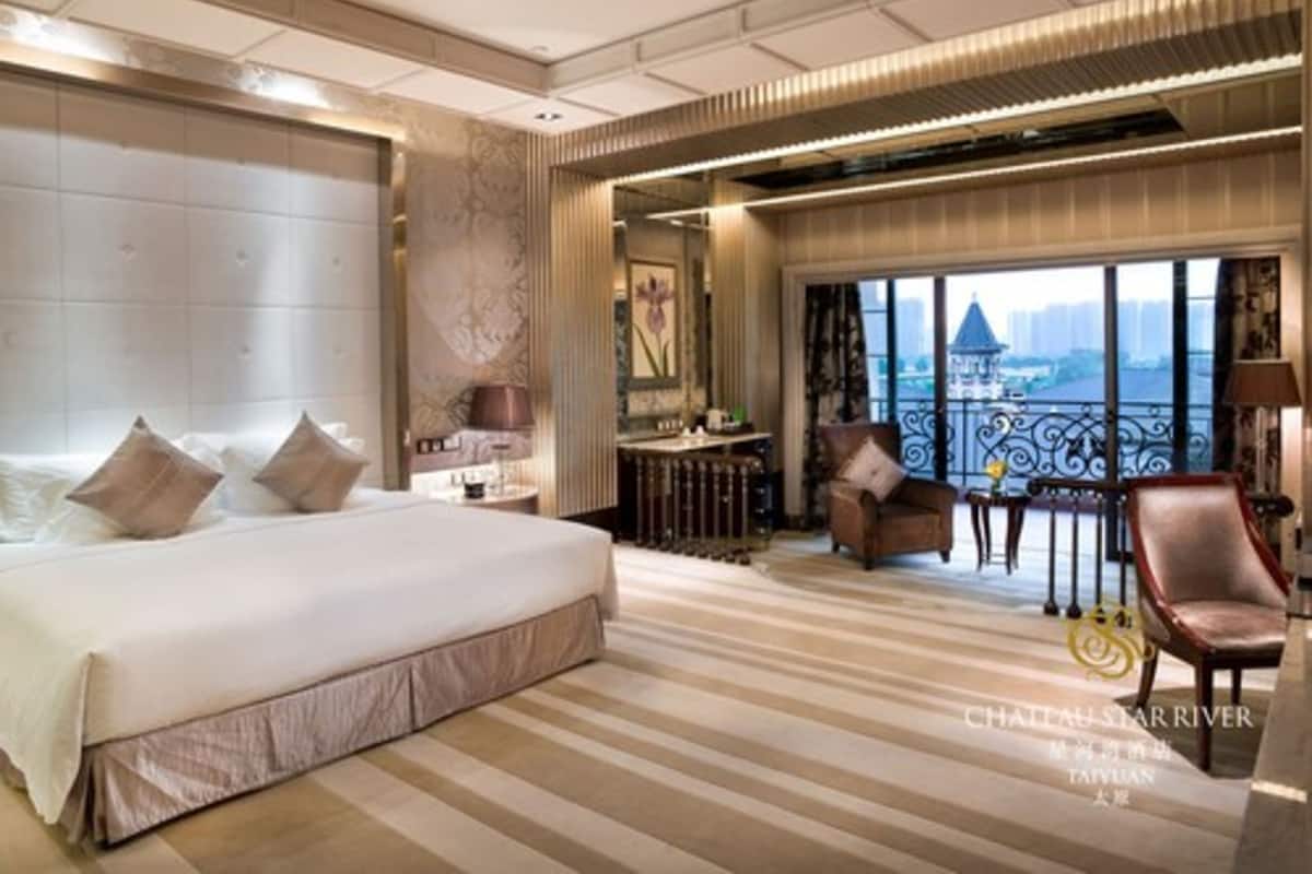 Ein geräumiges Hotelzimmer mit einem großen Bett, einer Sitzecke mit Blick und einem Balkon.