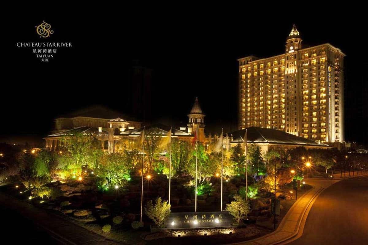 Ein beleuchtetes Hotel bei Nacht, groß mit einem markanten Turm und klassischer Architektur.