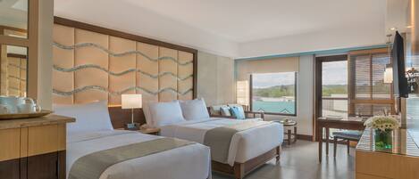 A hotel room with two beds, a desk, a chair, a TV, and a view of the outdoors.