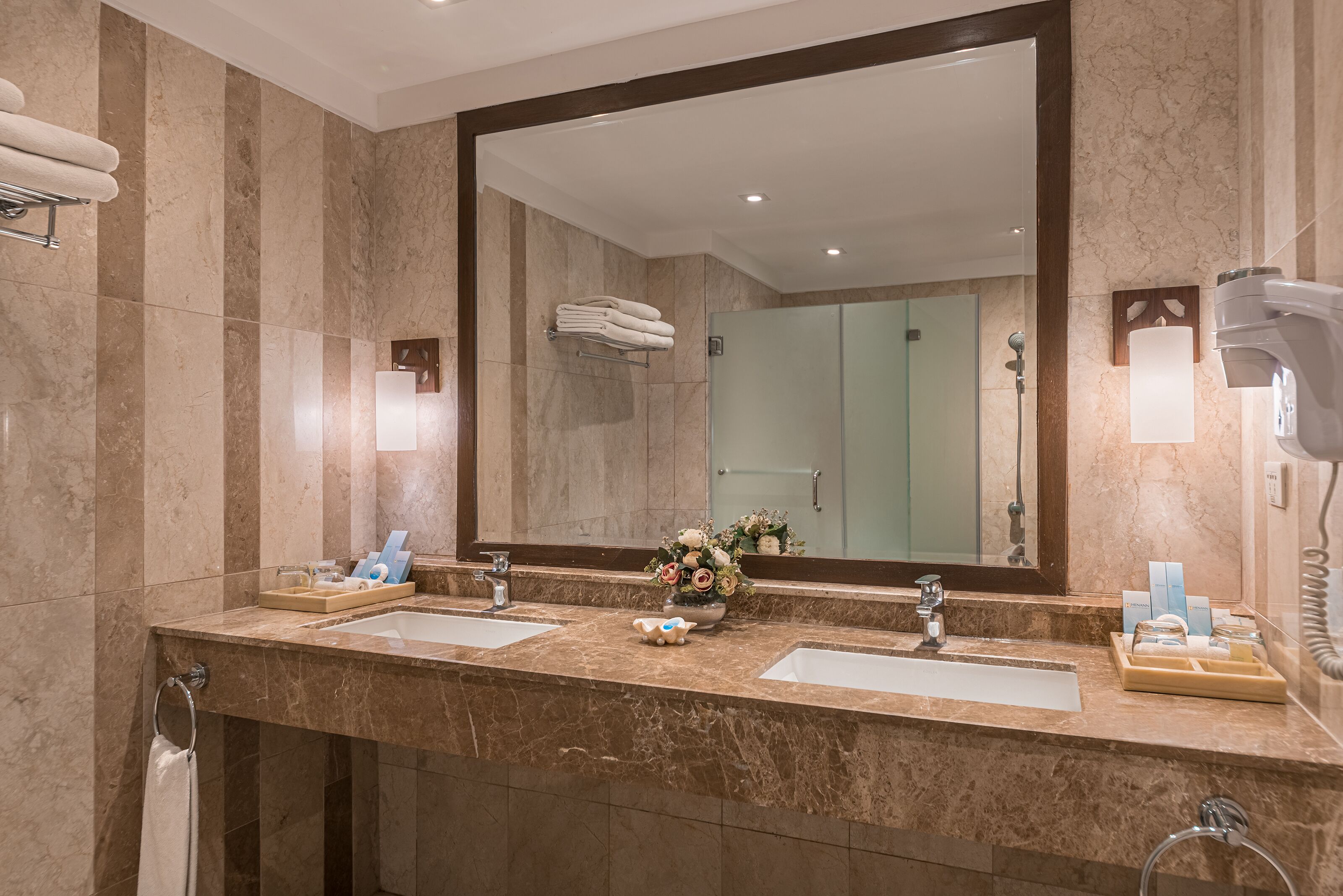A modern bathroom with two sinks, a large mirror, and a shower area.