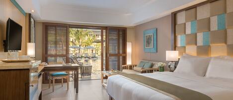 Habitación de hotel con una cama grande, un escritorio con silla, televisor y vistas al área exterior.