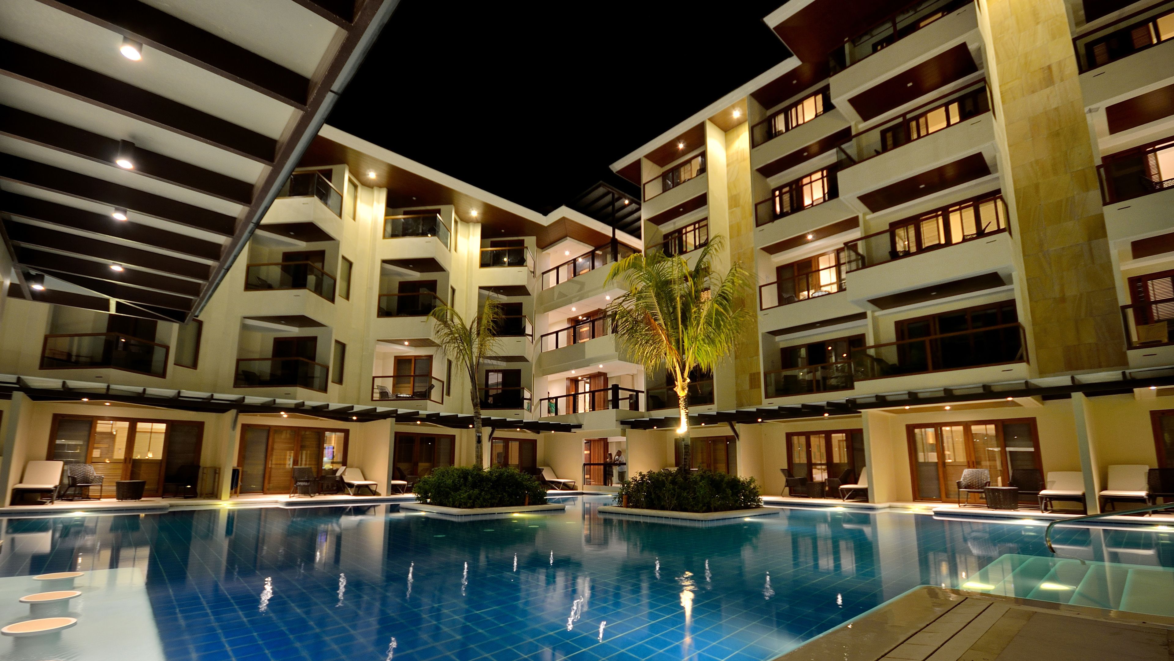 A multi-story hotel with a swimming pool, balconies, and outdoor seating areas.