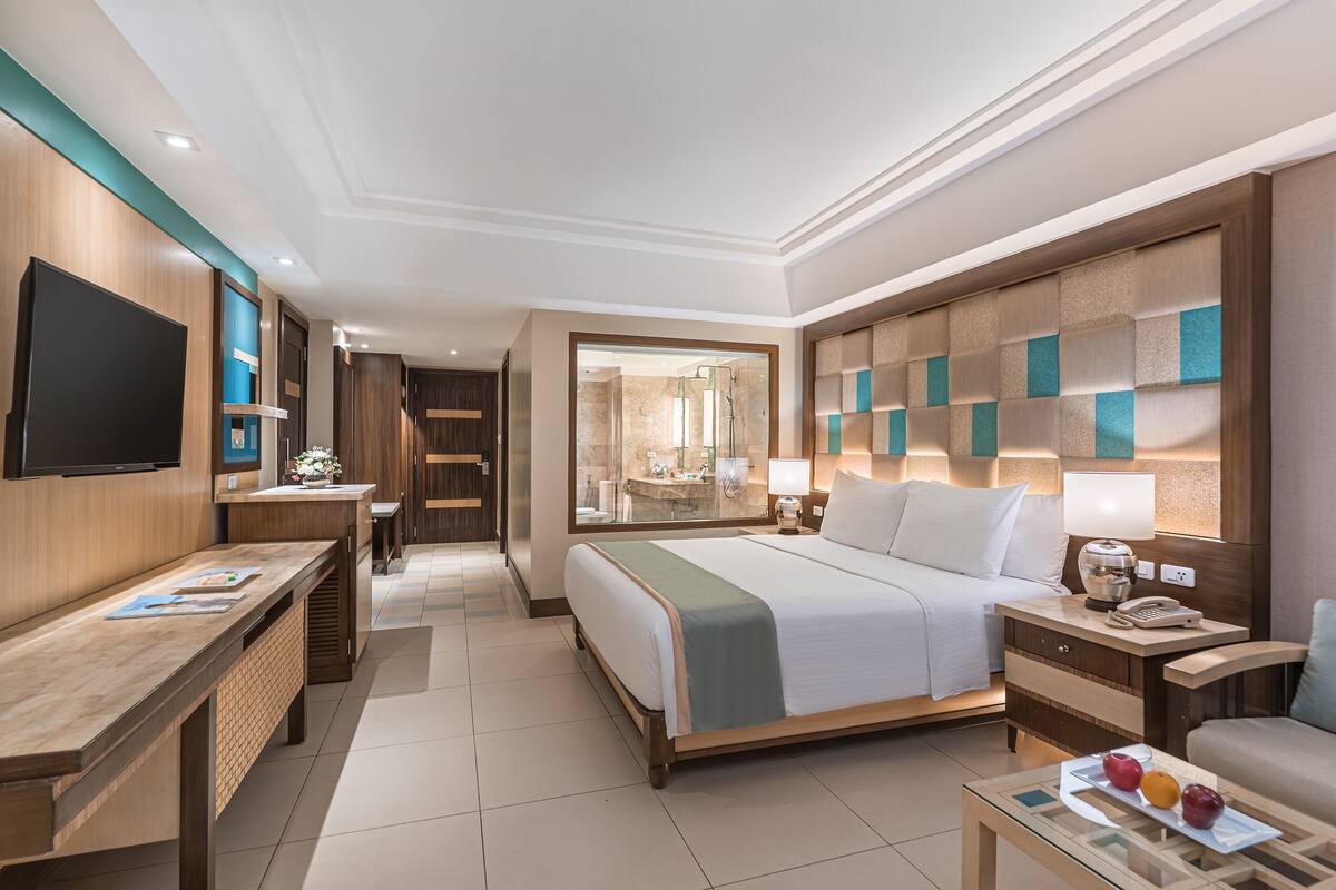 A hotel room with a bed, bedside table, desk, and a TV.