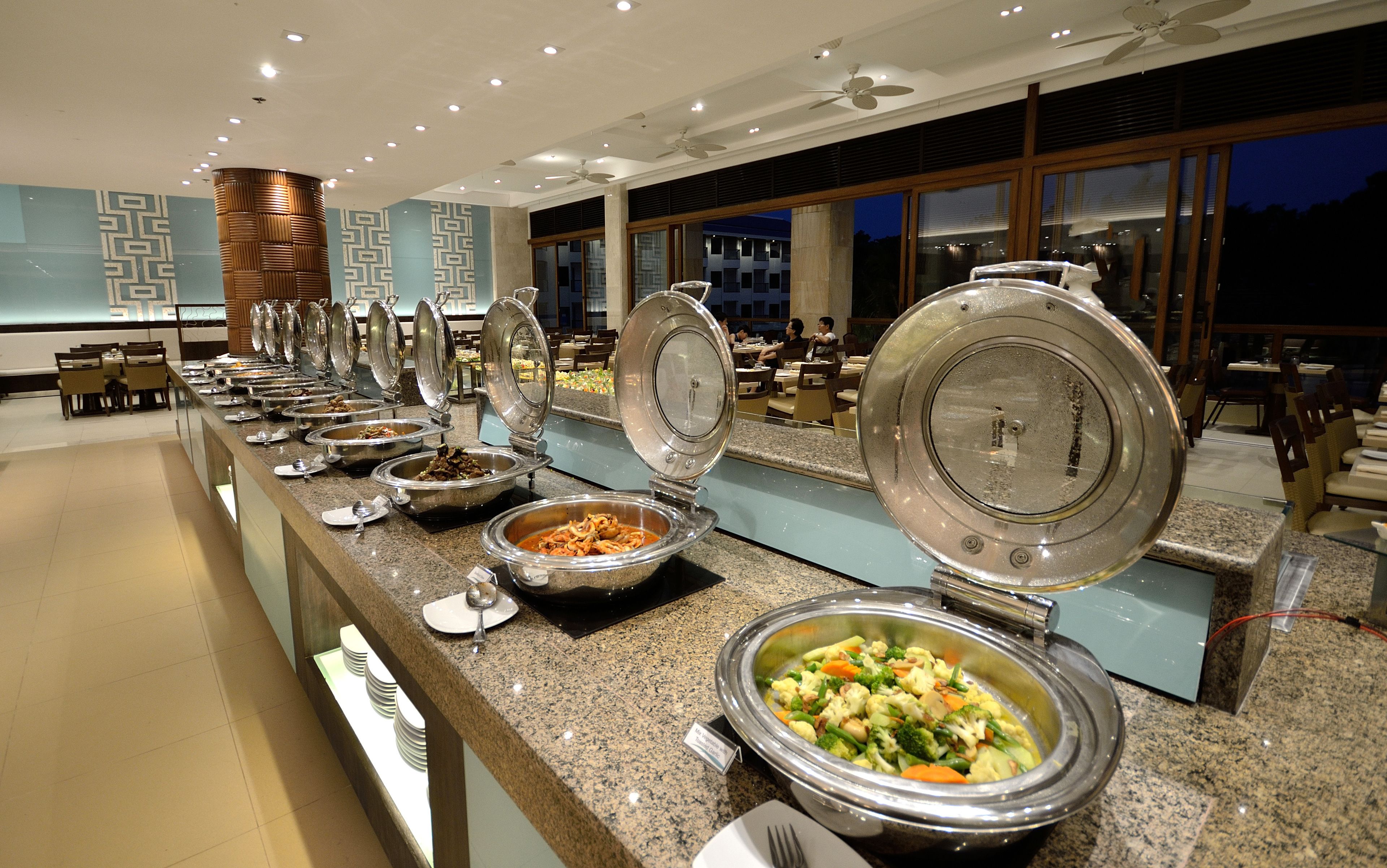 A buffet setup with multiple serving stations, each with a large bowl of food and a lid.