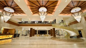 A spacious lobby with a central staircase, chandeliers, and a reception desk. - Henann Resort Alona Beach (Panglao)