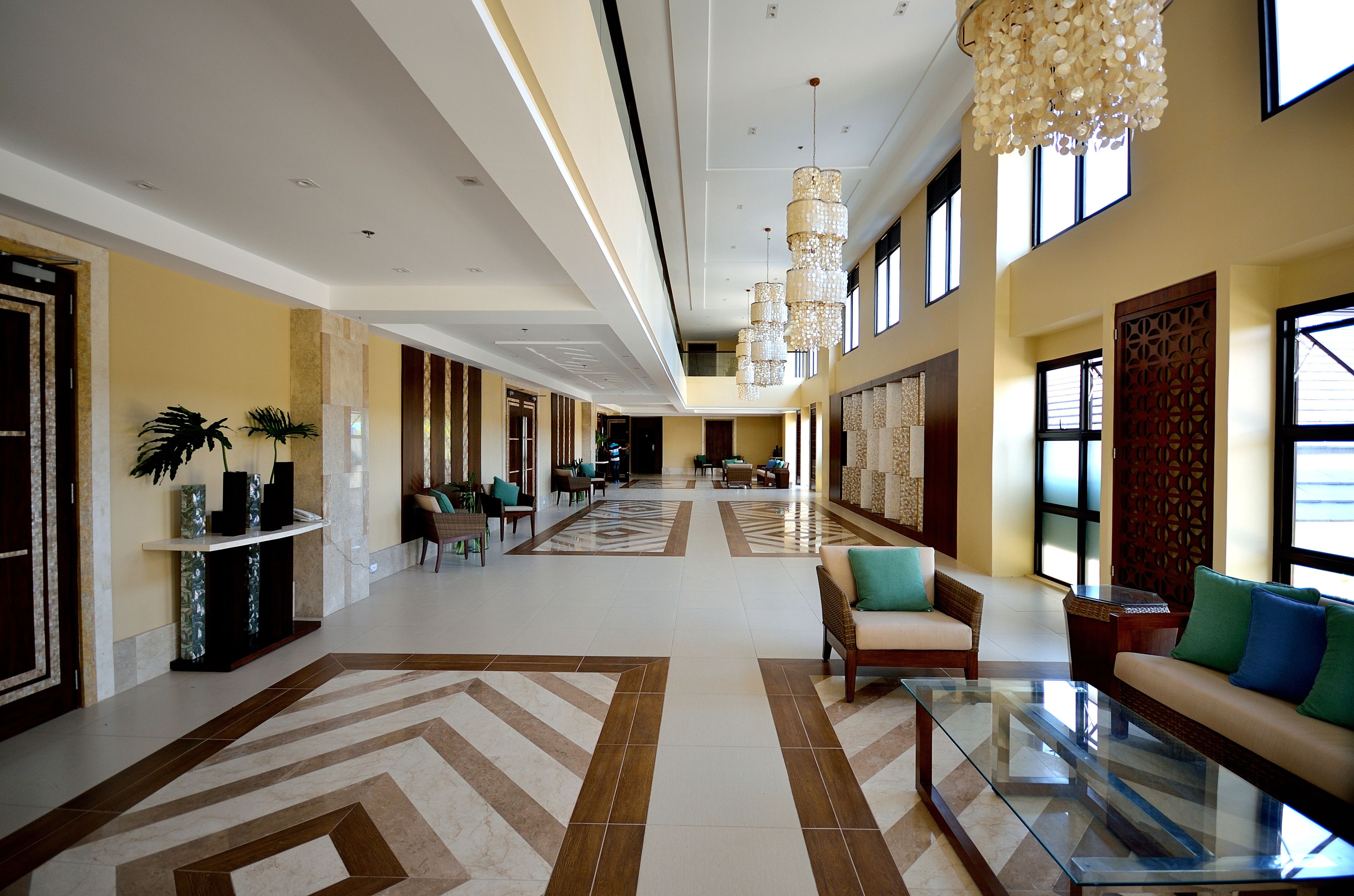 A spacious lobby with a high ceiling, chandeliers, a seating area with sofas, and a reception desk.