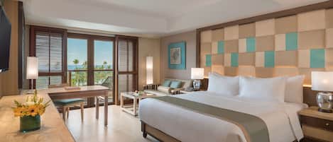 Habitación de hotel con una cama grande, un escritorio, una silla, un televisor y vista a palmeras.