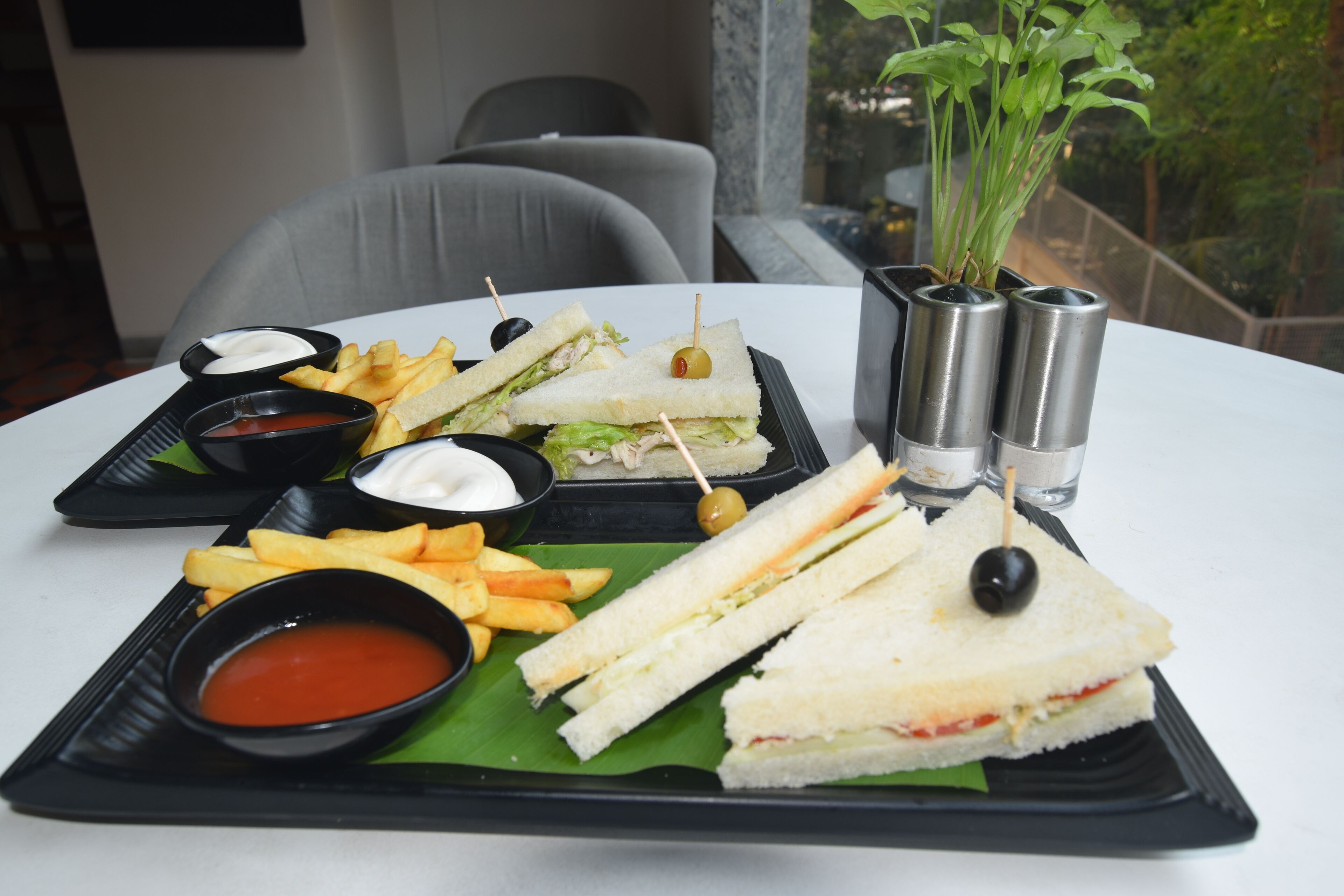 A tray with sandwiches, fries, and dipping sauces on a table.