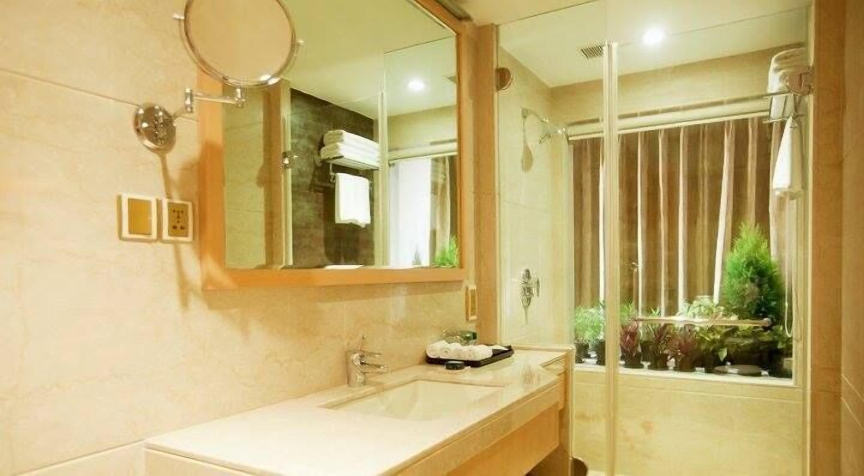 A bathroom with a sink, mirror, and shower.
