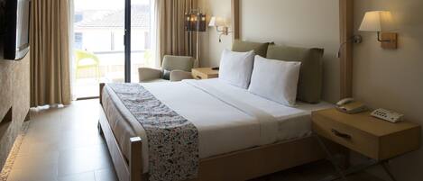 A hotel room with a large bed, bedside tables, a TV, and a view of the outside.