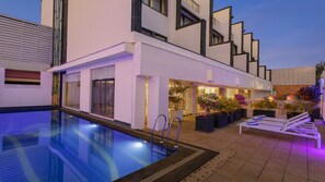 A modern building with a swimming pool, outdoor seating, and potted plants. - Ginger Dona Paula (Panaji)