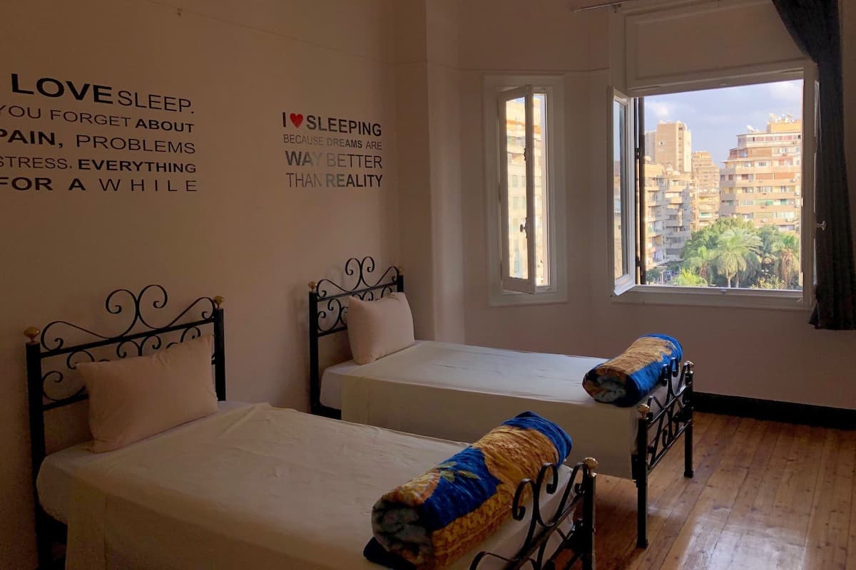 Un dormitorio con dos camas, una ventana con cortinas y una decoración de pared inspiradora.