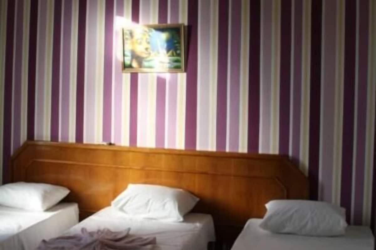 Habitación de hotel con dos camas, cabecero de madera y papel tapiz a rayas.