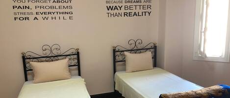 A room with two single beds, each with a decorative headboard and a pillow. The walls have motivational quotes about sleep.