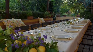 A long dining table set for a meal with white tablecloths, gold cutlery, and clear glassware. - La Terra del Mezzo (Riposto)