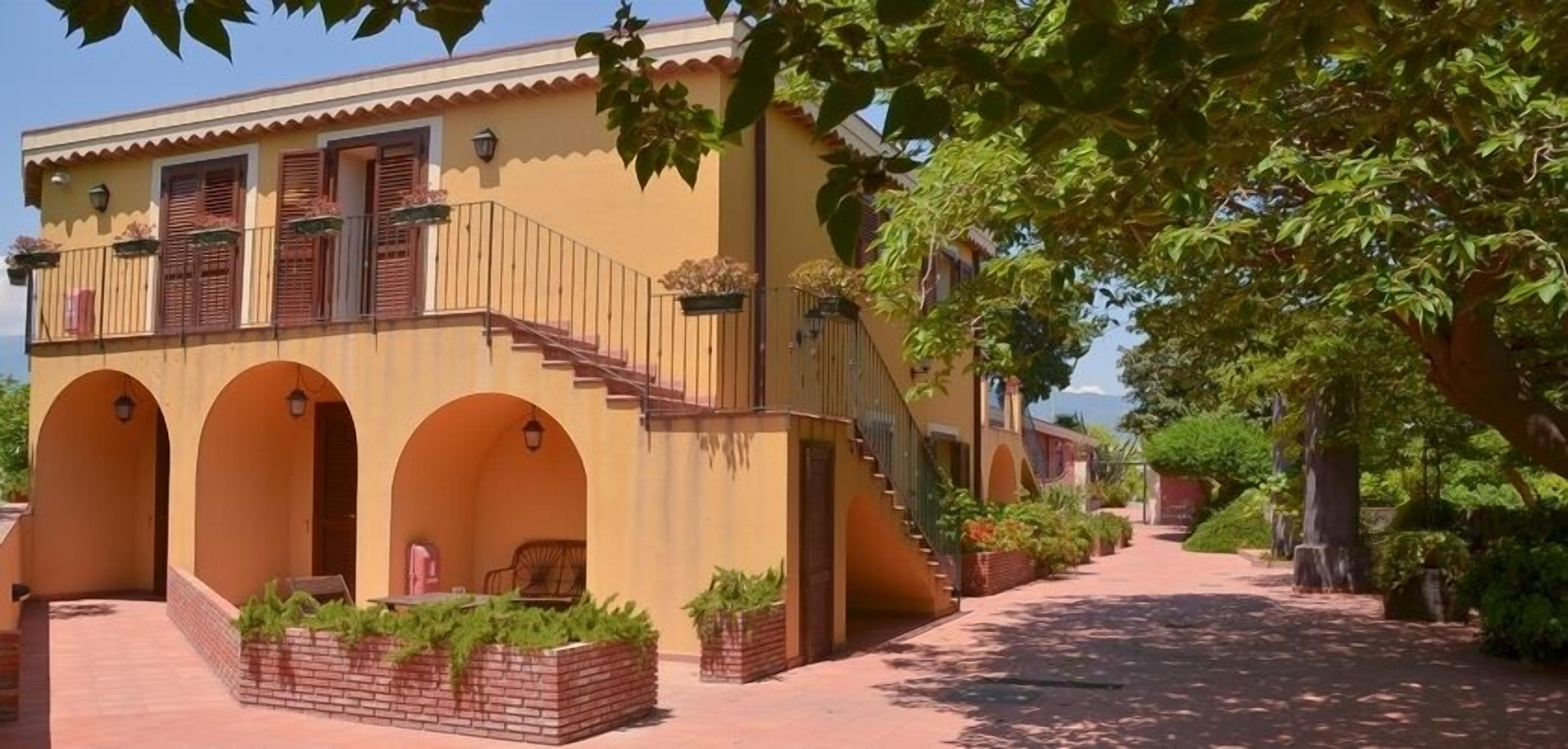 Un edificio giallo con portali ad arco e una scala che conduce a un balcone.
