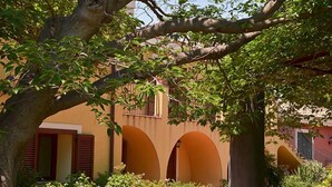 A building with arched windows and a tree in the foreground. - La Terra del Mezzo (Riposto)